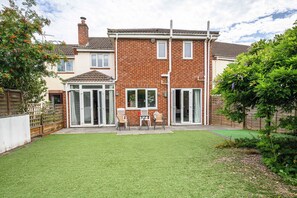 A two-story house with a brick facade, large windows, and a grassy backyard. - Howard Road Sleeps 7 -5 Bedrooms | Parking |Garden (Bristol)