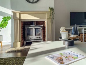 A modern living room with a fireplace, a television, and a magazine on the table. - Howard Road Sleeps 7 -5 Bedrooms | Parking |Garden (Bristol)