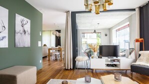 En moderne stue med sofa, sofabord, fjernsyn og spiseområde.