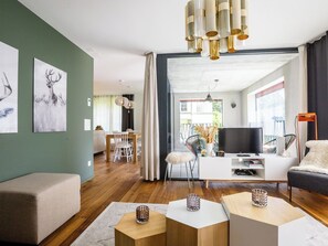 A modern living room with a sofa, coffee table, TV, and dining area. - Haus Burgermeister Wohnung Erzhorn Appartement/Fewo, Dusche oder Bad, WC, 4-Bett by Interhome (Arosa)