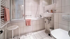 Moderni kylpyhuone, jossa on lasinen suihkuseinä, valkoinen pesuallas ja wc-istuin.