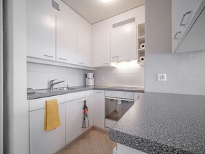 A modern kitchen with white cabinetry, a granite countertop, and a built-in oven. - Bristol 41 Appartement/Fewo, Dusche oder Bad, WC, 4-Bettwohnung by Interhome (Arosa)