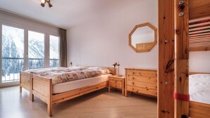 Makuuhuoneessa on puinen sänky, yöpöytä, lipasto, peili ja ikkuna, josta avautuu näkymä lumihuippuisiin vuoriin.