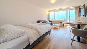 Hotellihuone, jossa on sänky, sohva, ruokapöytä ja televisio.