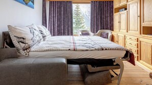 Una camera da letto con un letto, un divano, una sedia, mobili in legno e un quadro appeso al muro.