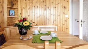 Un tavolo da pranzo in legno con un vaso di fiori, tazze e piattini bianchi e un sottopiatti verde.
