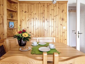 Ein Holztisch mit einer Blumenvase, weißen Tassen, Untertassen und einer grünen Tischmatte.