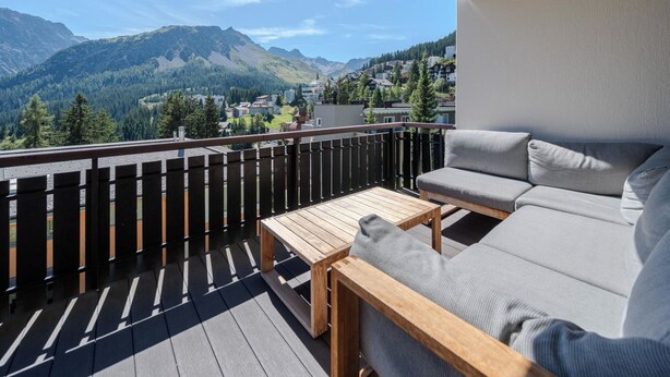 Ein Balkon mit Holzboden, einer Couch und einem kleinen Tisch.