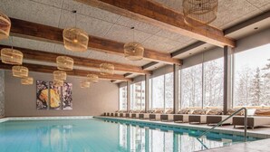 An indoor swimming pool with wooden beams, wicker pendant lights, and a seating area with cushions. - Rothornblick 11 by Arosa Holiday Appartement/Fewo, Bad, WC Rothornblick 11 by Interhome (Arosa)