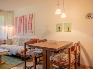 Ein gemütliches Wohnzimmer mit einer Couch, einem Holzessttisch und einem großen Gemälde an der Wand.