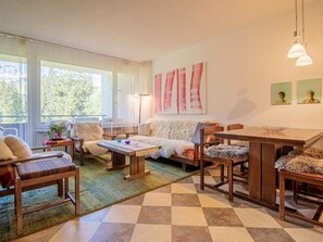 A cozy living room with a sofa, chairs, a coffee table, and a dining table. There are large windows with curtains, a lamp, and artwork on the wall. - Rothornblick 11 by Arosa Holiday Appartement/Fewo, Bad, WC Rothornblick 11 by Interhome (Arosa)