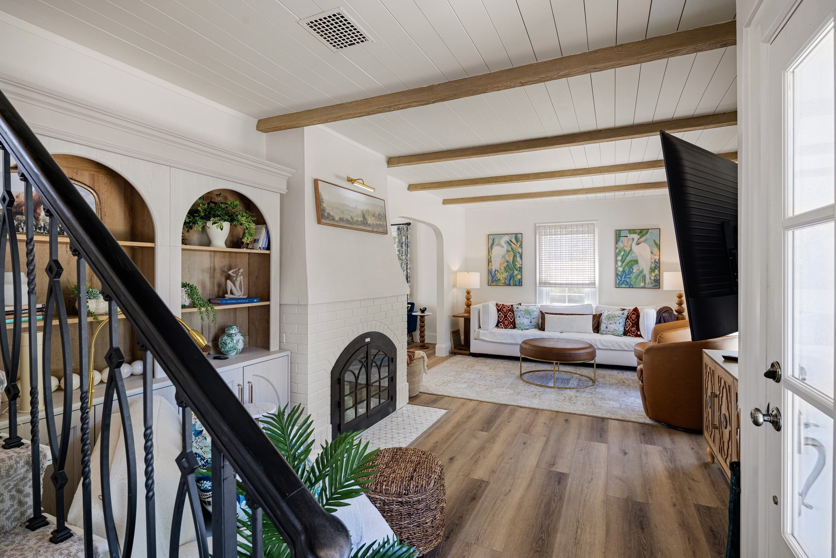 A spacious living area with a staircase, a fireplace, and a large window.