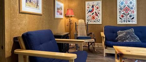 A cozy room with a wooden floor, a blue sofa, a wooden chair, and a lamp.