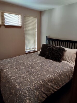 A bedroom with a bed, two windows with blinds, and a headboard. - Pet-friendly Condo With Patio - Creekside 83 1 Bedroom Condo (Arnold)