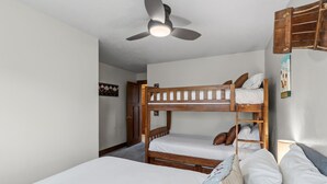 A bunk bed room with a ceiling fan, a door, and a wall-mounted sign. - Quiet Keystone Condo Near Slopes, Lake Dillon, Pool and Hot Tub (Keystone)