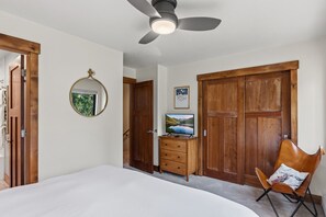 A bedroom with a bed, a ceiling fan, a wooden wardrobe, a dresser, a mirror, and a chair. - Quiet Keystone Condo Near Slopes, Lake Dillon, Pool and Hot Tub (Keystone)