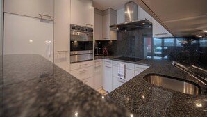 Una cocina moderna con electrodomésticos de acero inoxidable, encimeras de granito y un amplio ventanal.