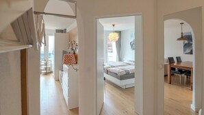 Amplia sala de estar con piso de madera, una mesa de comedor y un espejo grande que refleja la habitación.