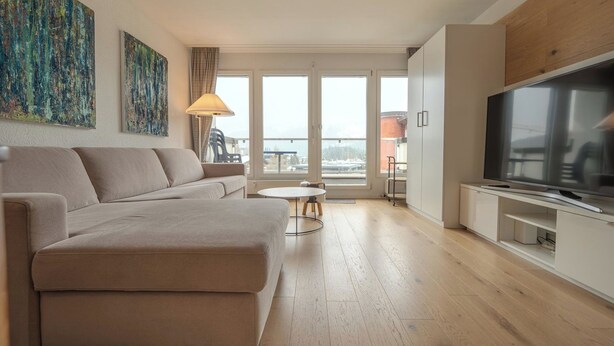 Una sala de estar moderna con sofá, televisión y balcón con vistas.