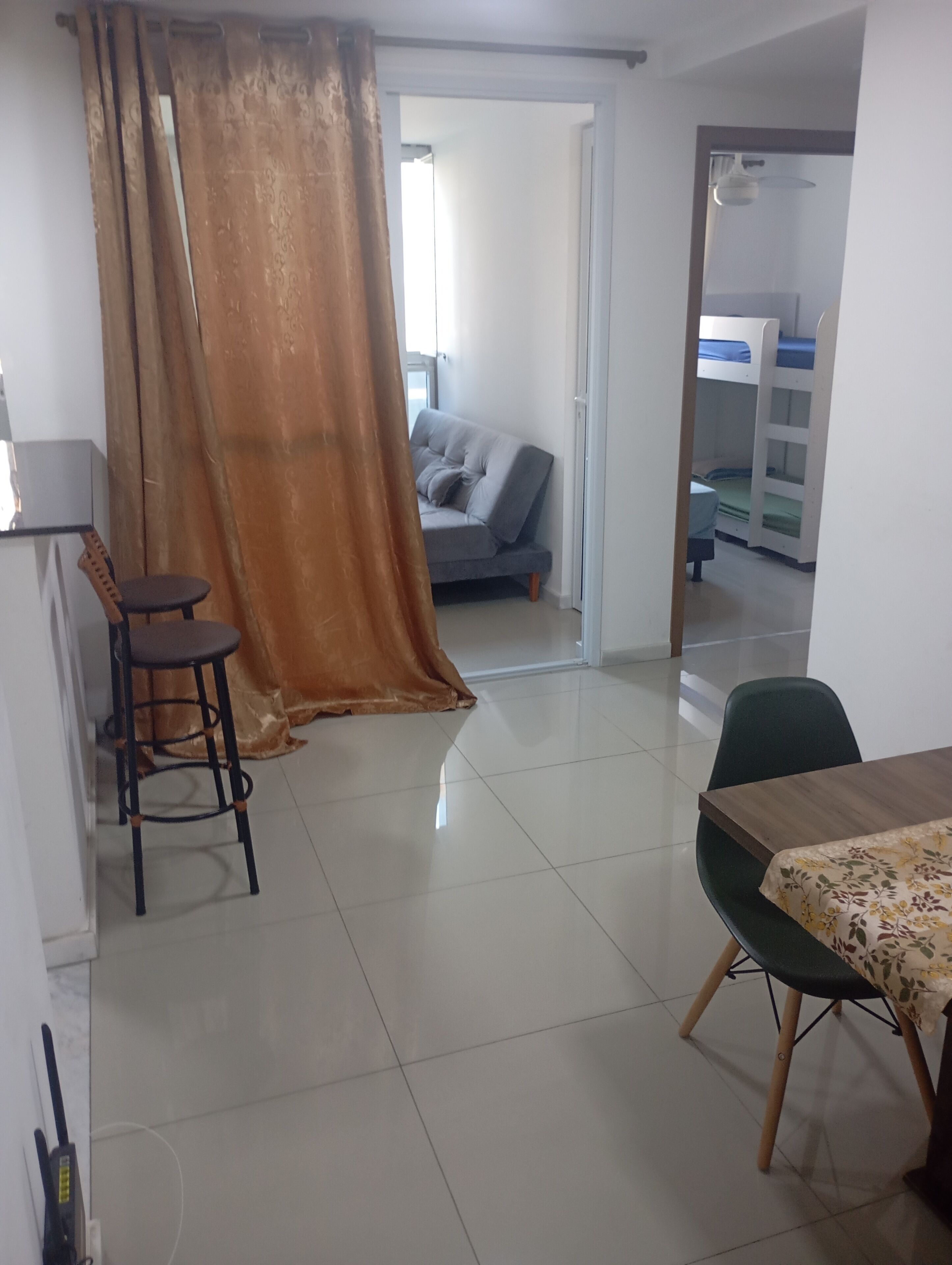 Una habitación con sofá, una mesa de comedor, una silla, una cortina y una cama litera al fondo.