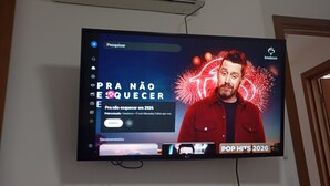 Un téléviseur fixé au mur diffuse un programme avec des feux d’artifice et du texte.