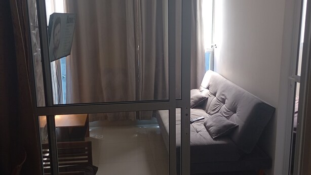 Une pièce dotée d’une porte-fenêtre coulissante qui donne sur un espace de vie comprenant un canapé et un fauteuil.
