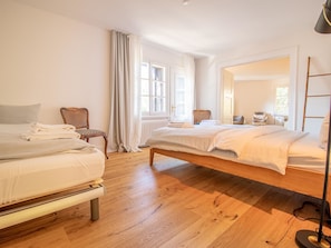 A hotel room with two beds, a chair, a radiator, and a large mirror. - Pradella EG by Arosa Holiday Appartement/Fewo, Dusche oder Bad, WC, 7-Bettwohnun by Interhome (Arosa)