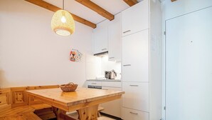 Une cuisine moderne avec des meubles en bois, un luminaire suspendu et un réfrigérateur blanc.
