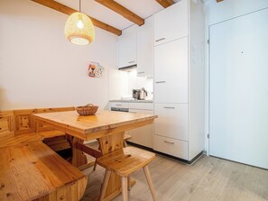 A modern kitchen with wooden furniture, a hanging light fixture, and a white refrigerator. - Irmella 10 by Arosa Holiday Appartement/Fewo,  , 3-Bettwohnung Irmella 10 by Interhome (Arosa)