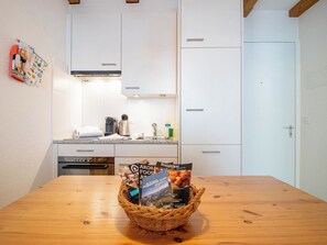 A kitchen with white cabinets, a wooden table, and a basket of brochures. - Irmella 10 by Arosa Holiday Appartement/Fewo,  , 3-Bettwohnung Irmella 10 by Interhome (Arosa)