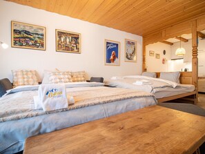 A hotel room with a wooden ceiling, a large bed with multiple pillows, a bench, and two paintings on the wall. - Irmella 10 by Arosa Holiday Appartement/Fewo,  , 3-Bettwohnung Irmella 10 by Interhome (Arosa)