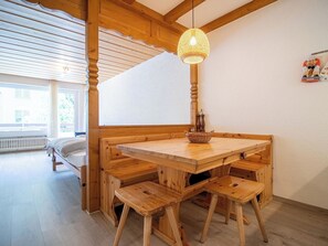 A wooden dining table with benches, a hanging light fixture, and a window with a view. - Irmella 10 by Arosa Holiday Appartement/Fewo,  , 3-Bettwohnung Irmella 10 by Interhome (Arosa)