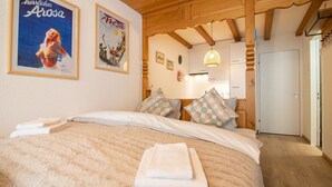 Une chambre avec un grand lit, deux affiches au mur et un plafond en bois.