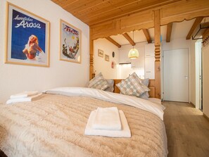 A bedroom with a large bed, two posters on the wall, and a wooden ceiling. - Irmella 10 by Arosa Holiday Appartement/Fewo,  , 3-Bettwohnung Irmella 10 by Interhome (Arosa)
