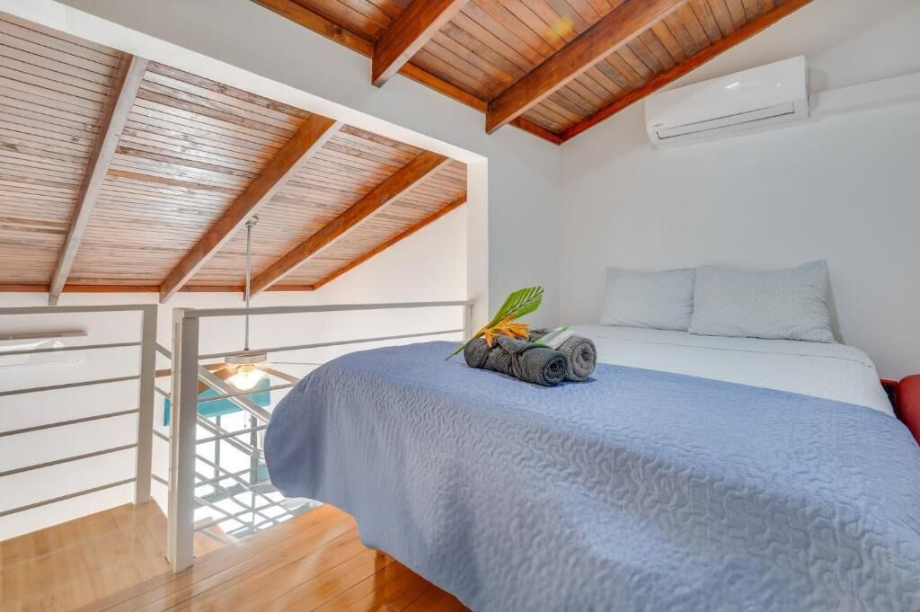 A bedroom with a bed, a wooden ceiling, and an air conditioning unit.