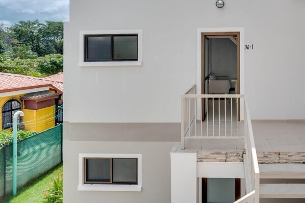 Un edificio de varios pisos con un balcón, una ventana y una puerta marcada '36-1'.