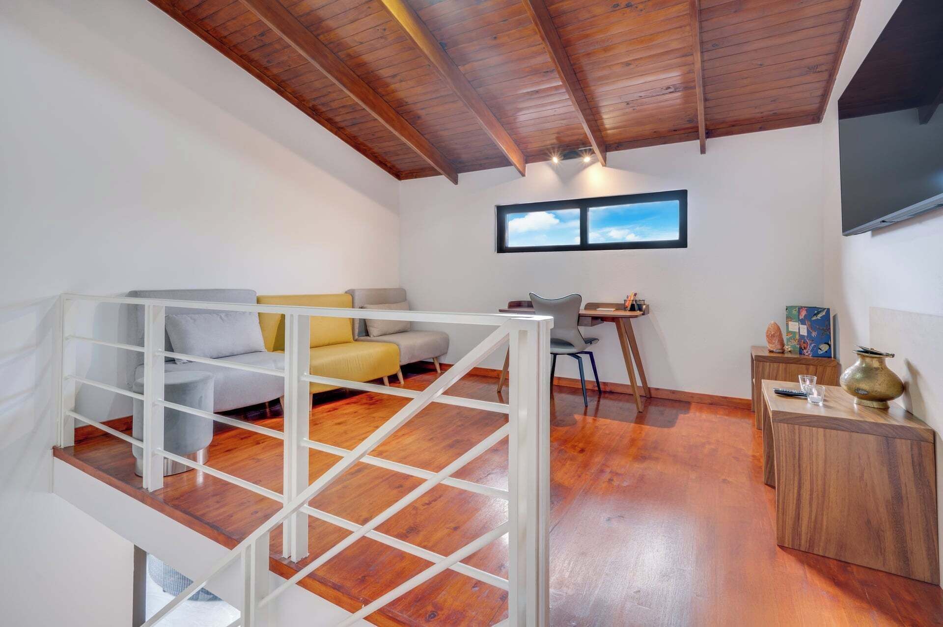 Ein Loft-Zimmer mit Holzbalkendecke, einer Couch, einem Esstisch und einem kleinen Schrank.
