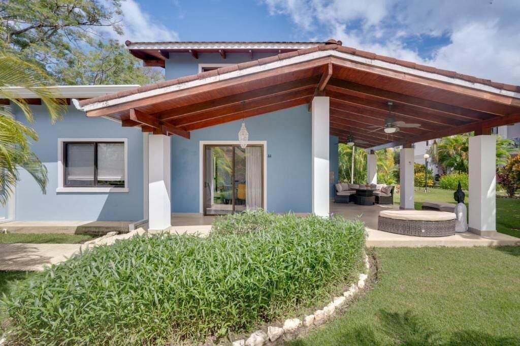Una casa moderna con un porche cubierto, un césped cuidado y un cielo despejado.