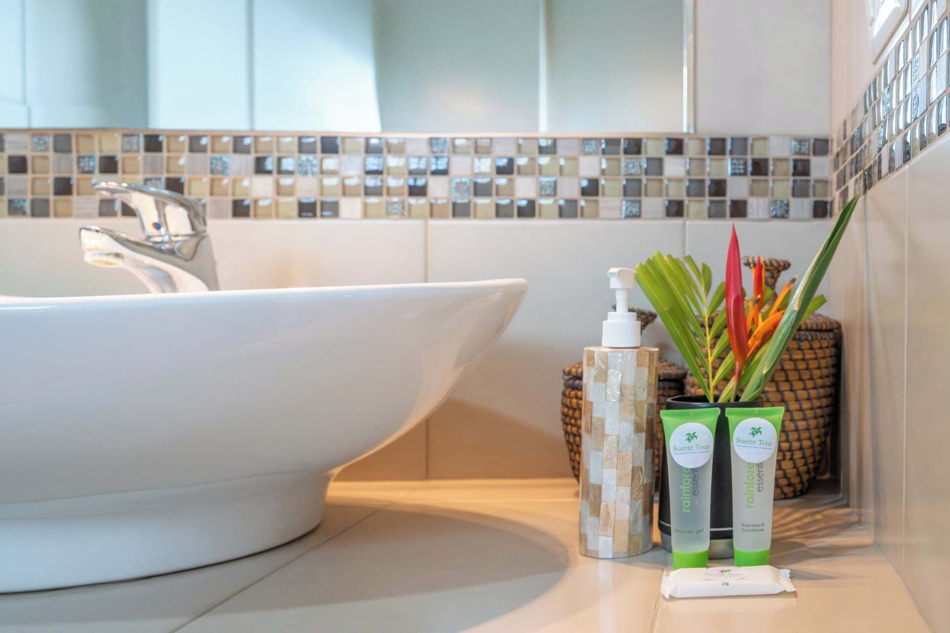 A bathroom with a white sink, a mirror, a tiled backsplash, and two green toiletry containers with pump dispensers.