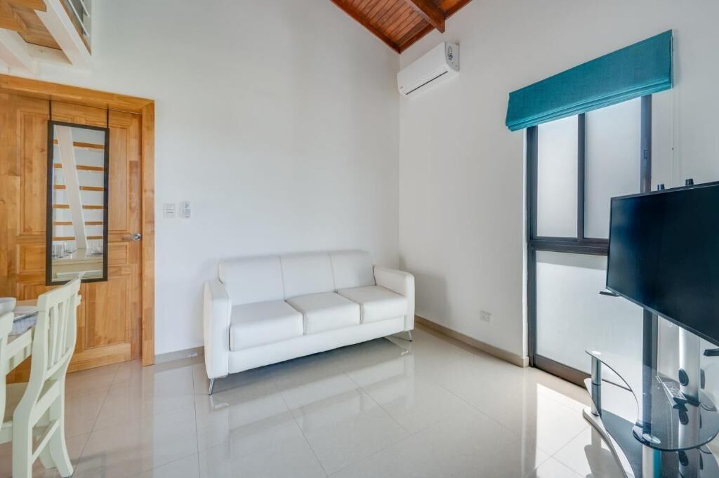 A modern living room with a white sofa, a television, and a wooden door.