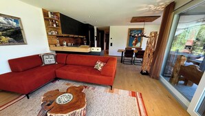 A modern living room with a red sofa, a wooden coffee table, and a dining area with a table and chairs. - Eden 3 by Arosa Holiday Appartement/Fewo, Bad, WC, 6-Bettwohnung by Interhome (Arosa)
