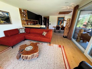 A modern living room with a red sofa, a wooden coffee table, and a dining area with a table and chairs. - Eden 3 by Arosa Holiday Appartement/Fewo, Bad, WC, 6-Bettwohnung by Interhome (Arosa)