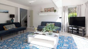 En moderne stue med sofa, sofabord, fjernsyn og en trappe.