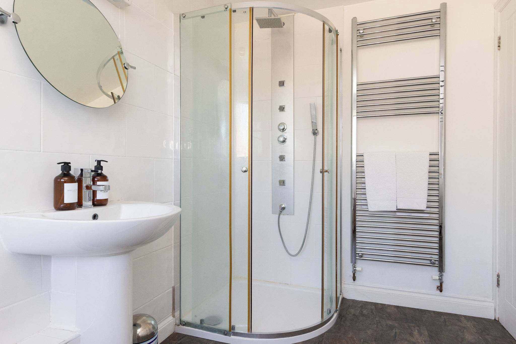 A modern bathroom with a glass-enclosed shower, a white sink, and a towel rack.