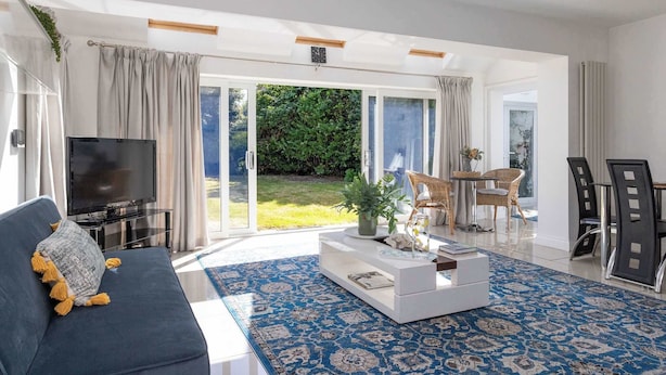 En moderne stue med sofa, sofabord, fjernsyn og et spiseområde med stole og bord.