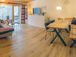 A cozy living room with a sofa, a dining table with chairs, a TV, and a bookshelf. - I dr Rehwiesa A25 Appartement/Fewo, Bad, WC, 3-Bettwohnung by Interhome (Arosa)