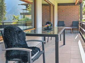 A balcony with a glass table, two chairs, and a potted plant. - I dr Rehwiesa A25 Appartement/Fewo, Bad, WC, 3-Bettwohnung by Interhome (Arosa)