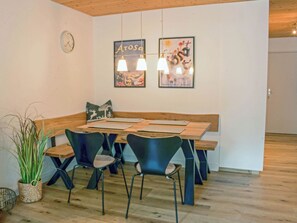 A dining area with a wooden table and chairs, a clock on the wall, and two framed pictures above the table. - I dr Rehwiesa A25 Appartement/Fewo, Bad, WC, 3-Bettwohnung by Interhome (Arosa)