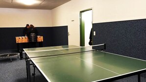 Pingispöytä, jossa on verkko, huoneessa, jossa on ovi ja seinä, jossa on tumma paneelilevy.