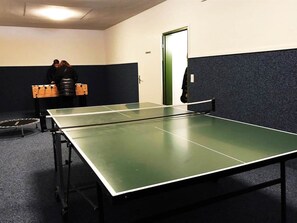 A ping pong table with a net in a room with a door and a wall with a dark panel. - I dr Rehwiesa A25 Appartement/Fewo, Bad, WC, 3-Bettwohnung by Interhome (Arosa)